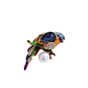 Colorful parrot brooch with blue enamel and crystal accents on a minimalist white base