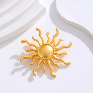 Macro detail of sunburst brooch with matte gold finish and wavy rays on white stone
