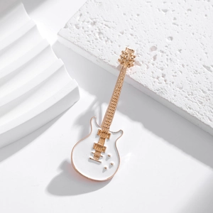 Dettaglio di una spilla a forma di chitarra elettrica bianca con bordi dorati e finiture curate
