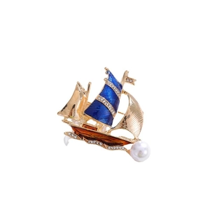 Golden sailboat brooch with blue enamel and pearl on a clean white background