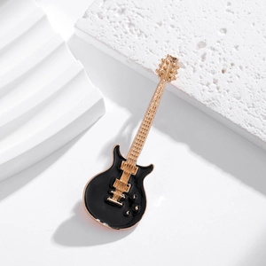 Dettaglio ravvicinato di una spilla vintage a forma di chitarra elettrica nera e oro