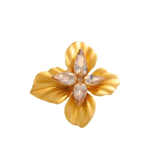 Vintage gold flower brooch with frosted petals and pear-shaped crystals on white background