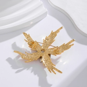 Elegant gold starfish brooch with crystal stones on a textured plaster stand
