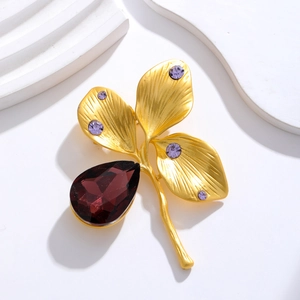Detail of vintage gold clover brooch featuring purple teardrop crystal and leaf texture