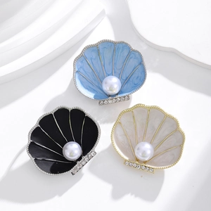 Elegant shell brooches with central pearls and rhinestones in blue, black, and cream colors