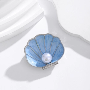 Detail of blue shell brooch with pearl inlay and crystals on a clean background