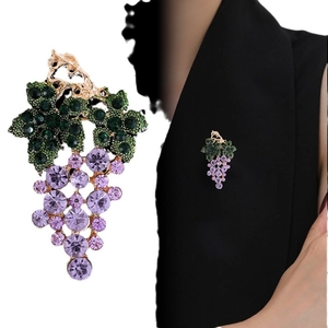 Broche raisin dorée avec cristaux violets et verts sur le revers d'un blazer noir