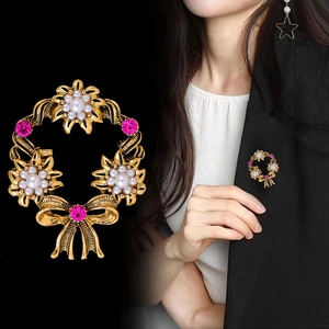 Vintage gold wreath brooch with pearls and purple crystals on black blazer lapel