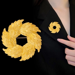 Golden olive branch wreath brooch with feather texture on a black suit lapel