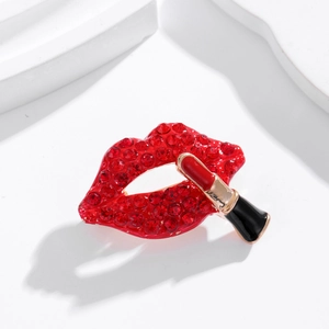 Détail de la broche lèvres en strass rouges et rouge à lèvres sur fond blanc minimaliste