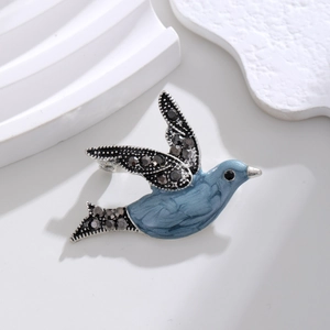 Detailed view of flying bird brooch with blue enamel and sparkling dark grey rhinestones