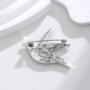 Detail view of the secure clasp and brushed metal texture on the bird brooch back