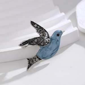 Detail of creative flying bird brooch featuring blue enamel and sparkling black rhinestones
