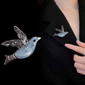 Detail view of a blue bird brooch with rhinestones on a black suit lapel