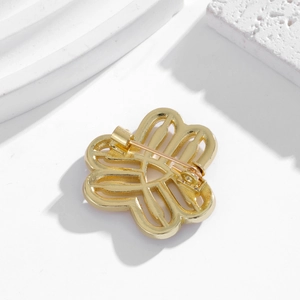 Golden hollow-out flower brooch with rhinestone detailing shown from the back view