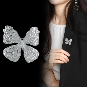Macro shot of silver butterfly brooch with hammered metal texture on black suit lapel