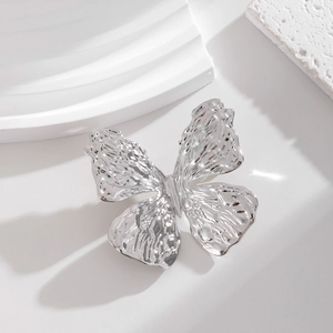Close-up of a silver butterfly brooch featuring a unique hammered metal texture and finish
