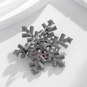 Exquisite snowflake brooch with red gemstone and gunmetal texture on a white background