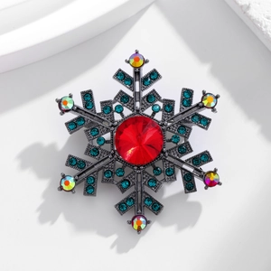 Detailed close-up of a snowflake brooch with red crystal and blue rhinestones on white