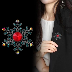 Snowflake brooch with faceted red center stone and blue rhinestones on black background
