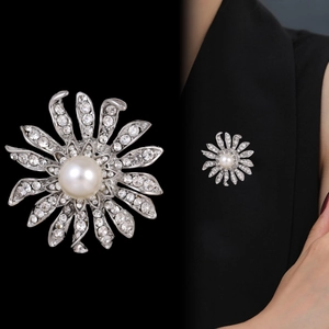 Broche fleur solaire argentée élégante avec cristaux scintillants et perle sur un blazer