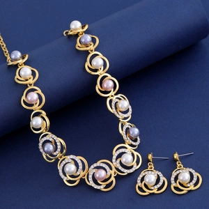 Détail d'une parure en or avec perles multicolores et strass brillants sur fond bleu marine