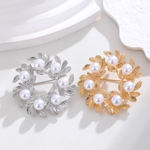 Elegant wreath brooch with matte gold finish and faux pearls on a clean white display