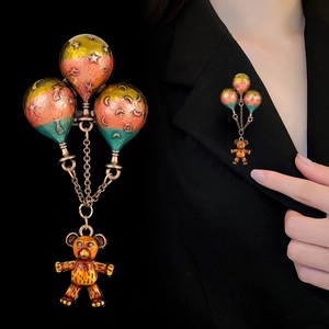 Detail view of hot air balloon bear brooch with colorful enamel balloons and golden chain
