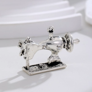 Macro shot of silver sewing machine brooch with white rhinestones and detailed vintage design