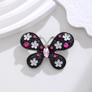 Detail shot of the butterfly brooch featuring black enamel wings and pink crystals