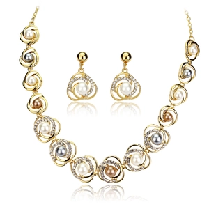Parure de bijoux fleur dorée avec perles colorées et cristaux sur fond blanc épuré