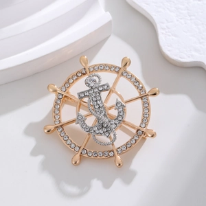 Detail of nautical helm and anchor brooch with silver crystals and gold plating