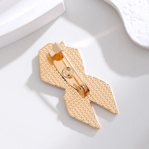 Detailed back view of a gold ribbon brooch showing the pin clasp and honeycomb texture