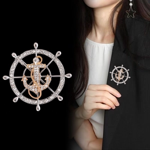 Macro shot of silver ship wheel and golden anchor brooch with sparkling rhinestones on suit