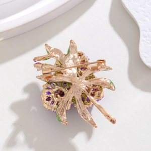 Pastel daisy flower brooch in gold plating with purple petals and green leaf accents