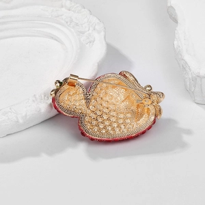 Detail view of the gold alloy base and safety pin clasp on the strawberry brooch