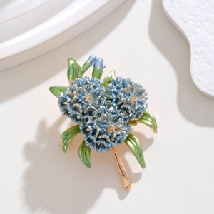 Detailed view of blue enamel daisy brooch with gold petals and green leaves on white background