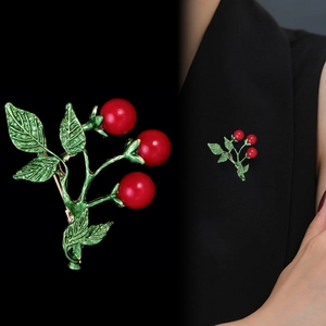 Detailed macro view and on-suit display of an elegant red cherry brooch with green leaves