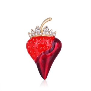 Close-up of strawberry brooch with red enamel and sparkling rhinestones on golden crown leaves