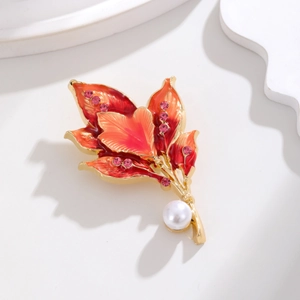 Detailed view of red enamel leaf brooch with shimmering crystals and a lustrous pearl