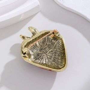 Detail view of vintage gold strawberry brooch back with safety pin and textured alloy finish