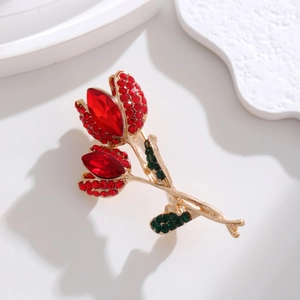 Detail shot of golden tulip brooch featuring vibrant red rhinestones and green crystal leaves