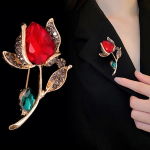 Elegante goldene Rosenbrosche mit rotem Tropfenstein und grünem Blatt auf Anzug