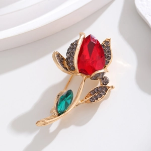 Detailansicht einer Rosenbrosche mit rotem Kristall und funkelnden Strass-Blüten