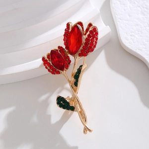 Detail of tulip brooch featuring red crystals and golden base in minimalist setting