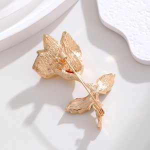 Golden rose flower brooch showing detailed texture and a secure pin on back side