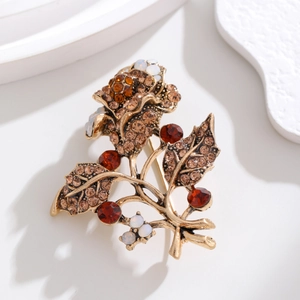 Detail view of vintage golden floral brooch with burgundy rhinestones on white platform