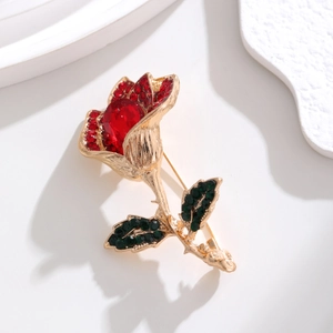 Macro view of rose brooch with red crystal petals and green rhinestone leaves