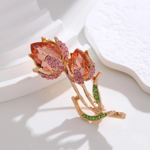 Macro view of crystal tulip brooch with orange rhinestones on gold base decor