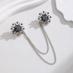 Macro detail of sunburst double brooch pins with dark gray crystal and silver chains